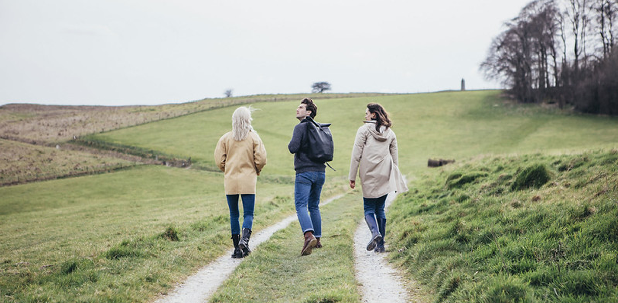 Three friends walking up a path on a Wiltshire hillside